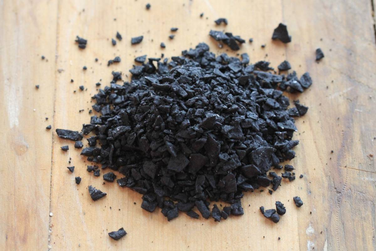 A handful of Charman biochar active on a wooden board