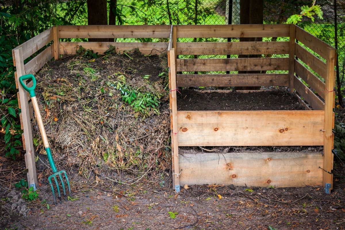 A two-bin compost bin with a garden fork