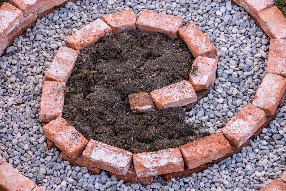 Adding gravel for drainage and soil to the herb spiral