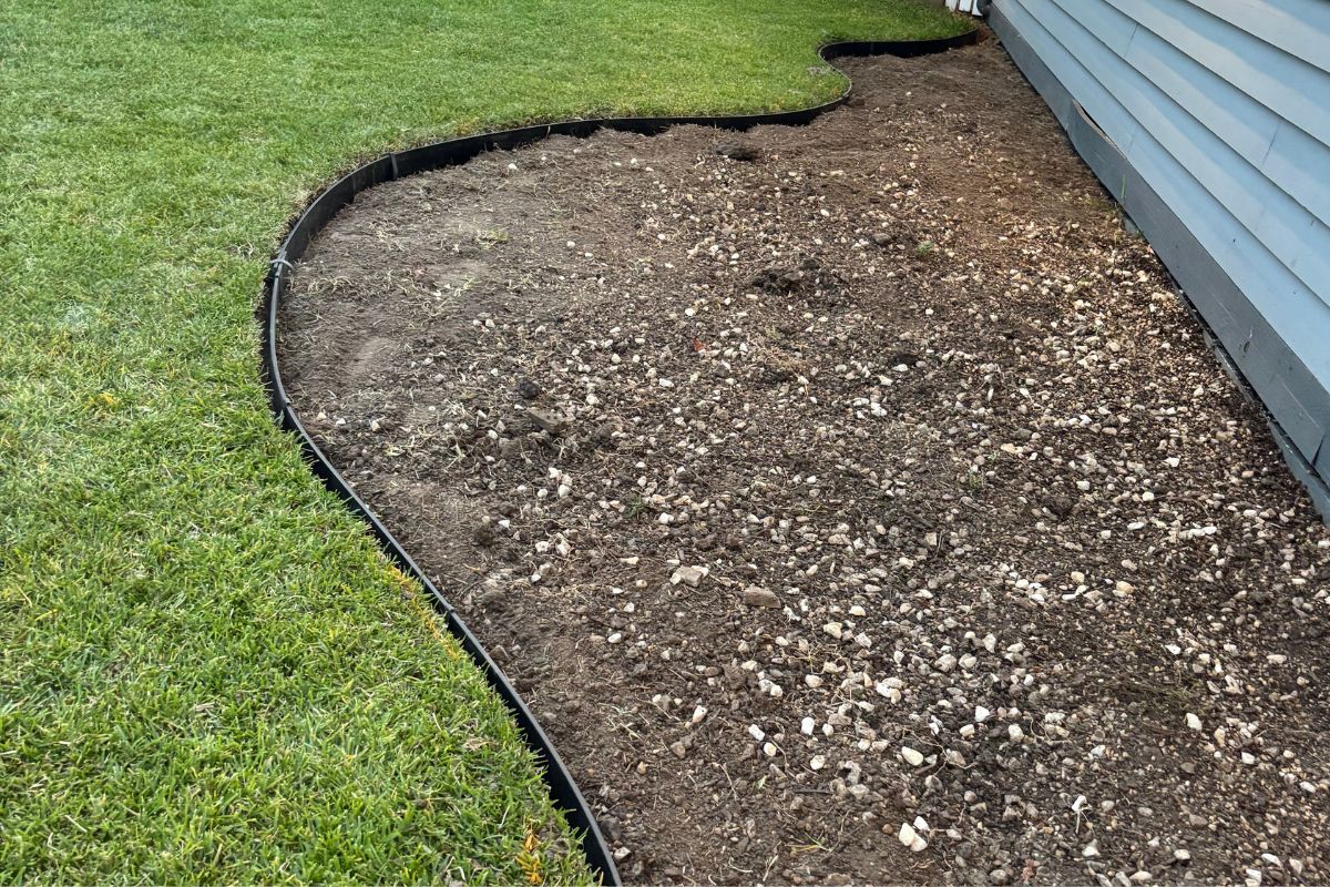 Black plastic garden edging installed for cottage garden bed