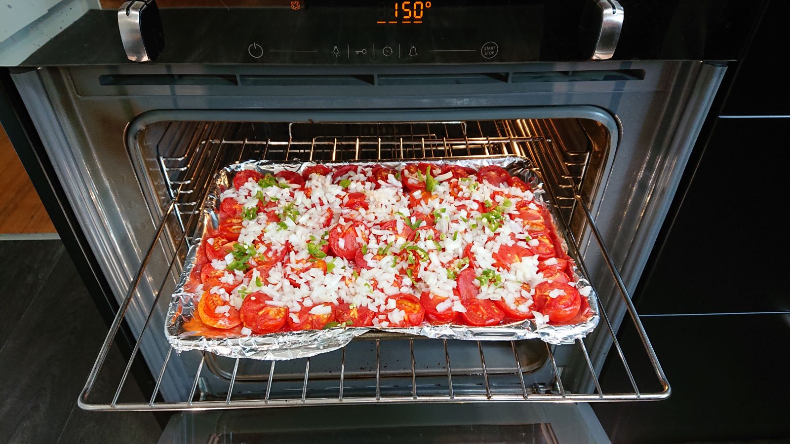 Two trays of roasted tomatoes sprinkled with chilli and onion