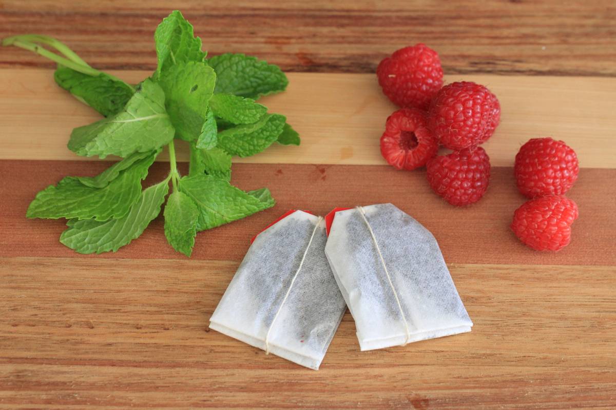 Ingredients for making raspberry mint iced tea: mint, fresh raspberries and tea bags