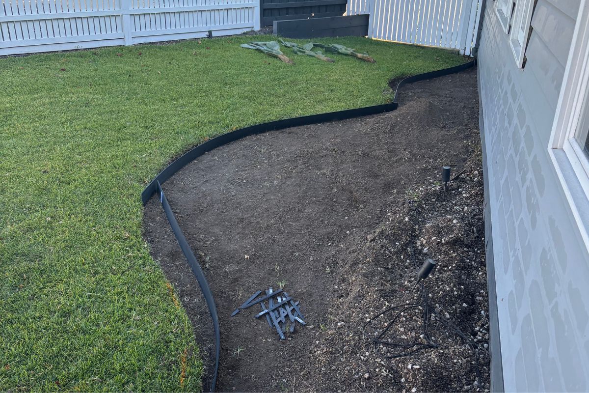 Laying out the black plastic garden edging for the cottage garden bed