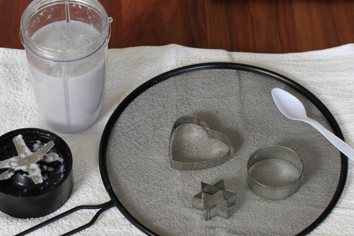 Blended paper pulp, a splatter guard and cookie cutters on a towel.