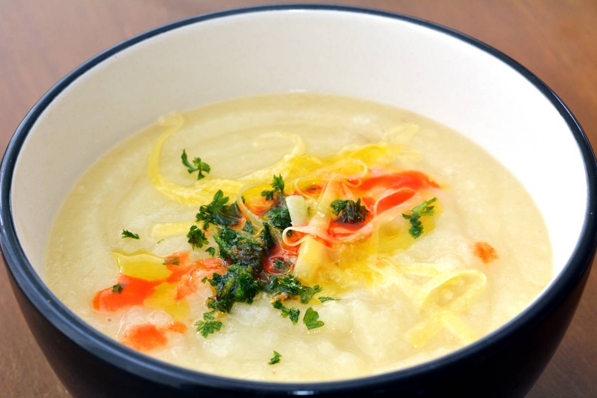 A photo of a bowl of parsnip soup, garnished with parsley and a red sauce