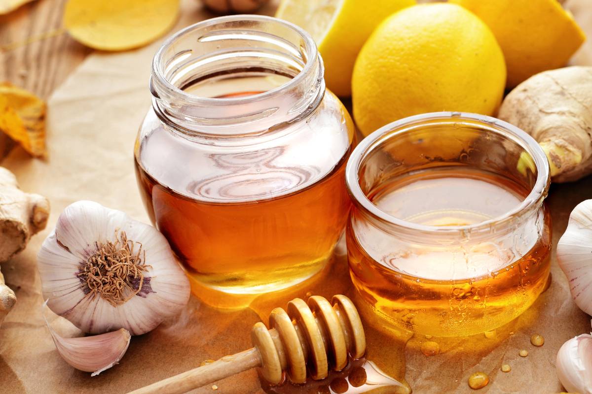 Two jars of honey and some garlic on a chopping board