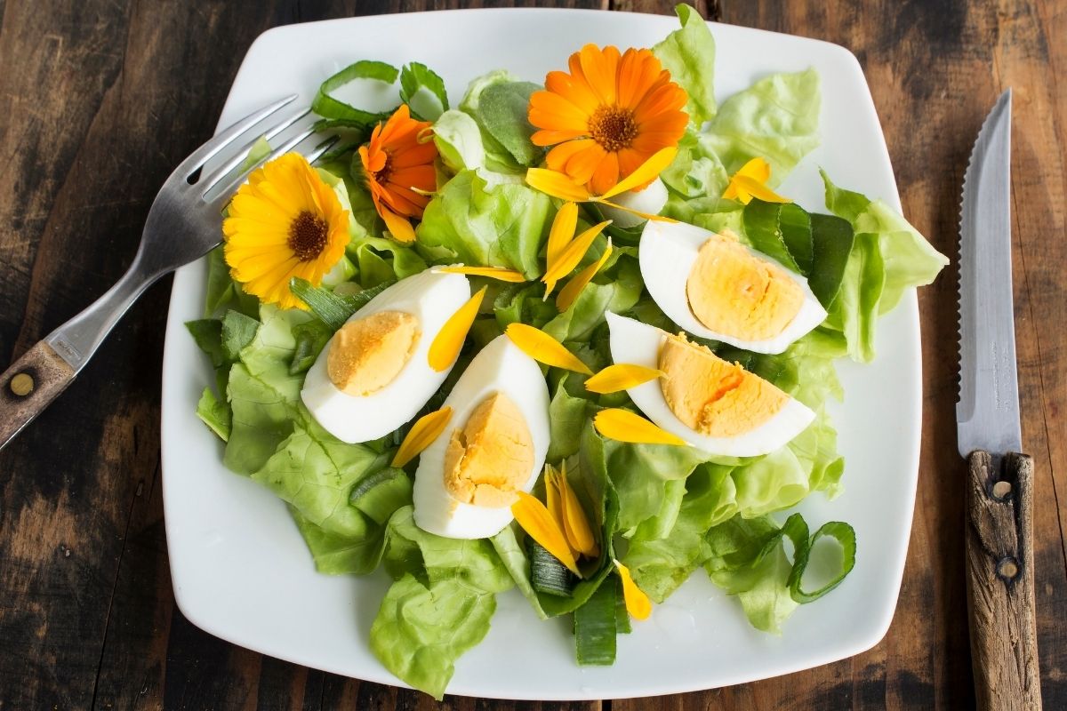 A plate of boiled eggs and salad garnished with calendula flowers