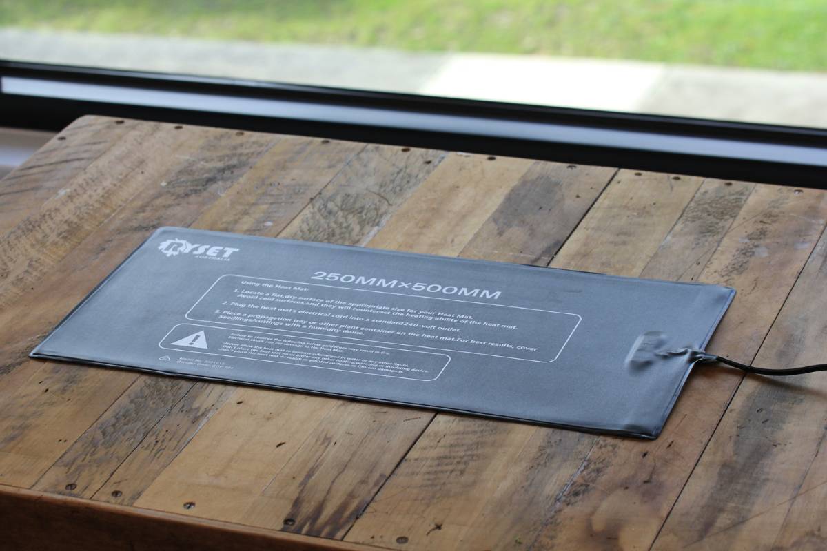 A photo of a heat mat lying flat on a wooden board next to a window