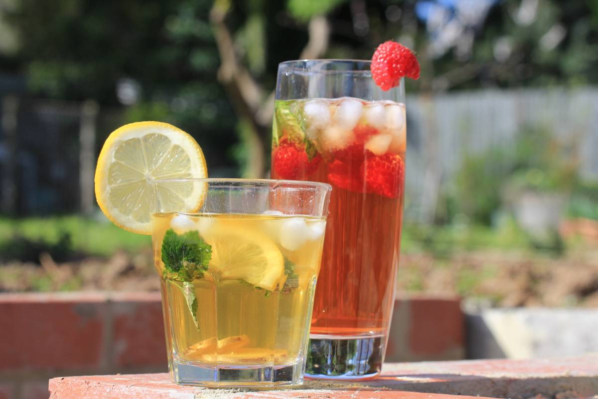 Two glasses of iced tea, one raspberry mint flavour the other ginger and lemon balm flavour